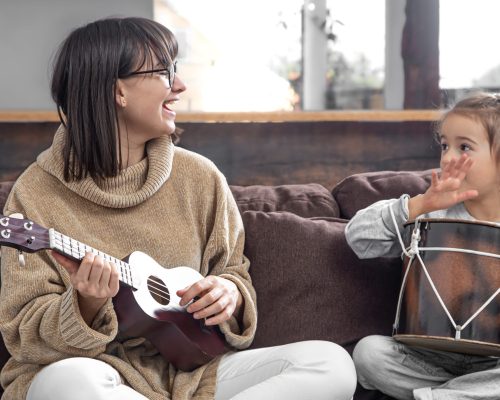 Mom plays with her daughter at home. Lessons on a musical instrument. Children's development and family values. The concept of children's friendship and family.